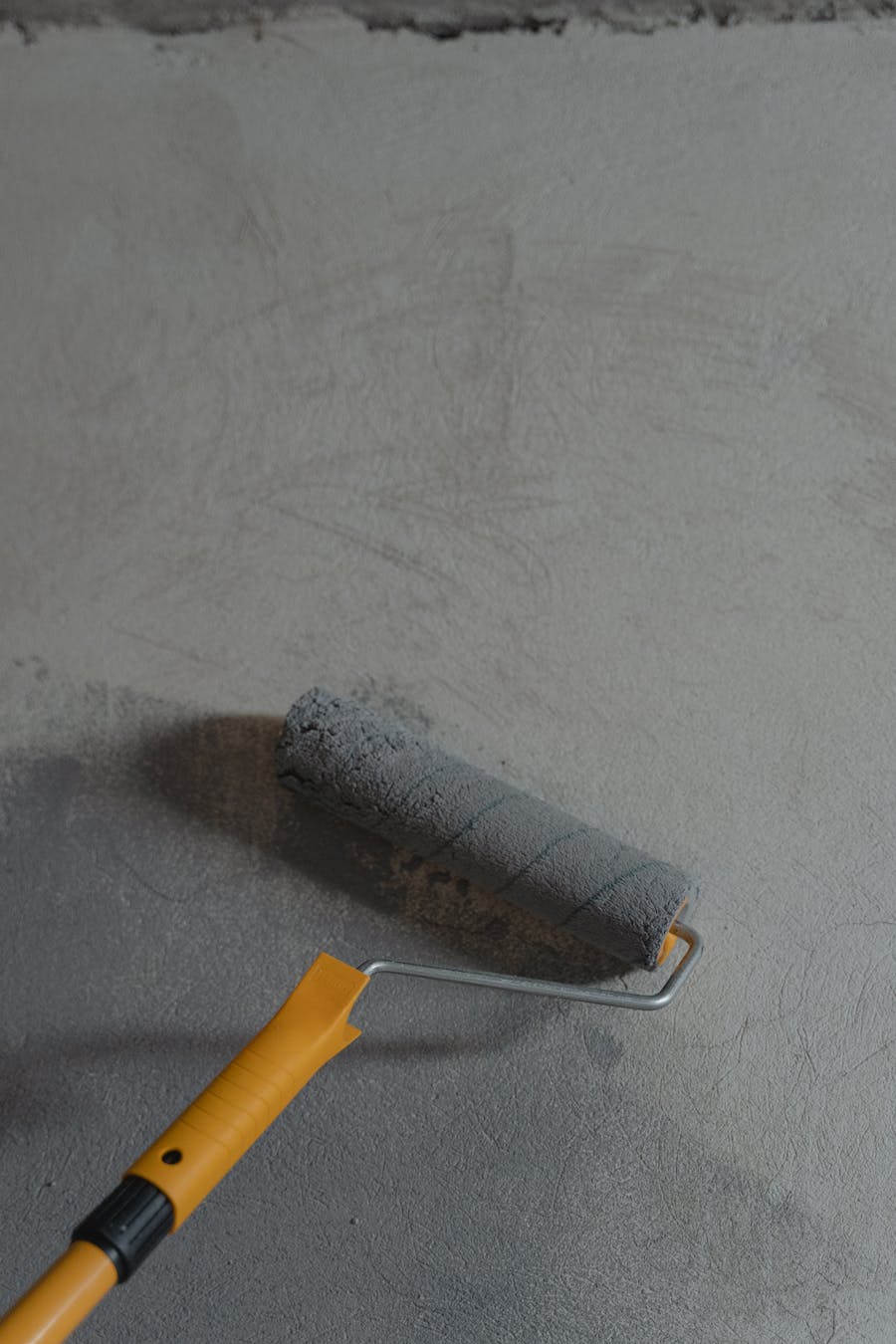 A paint roller applying grey paint to an interior wall